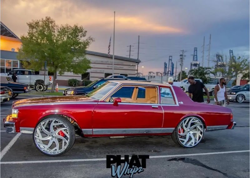 Red Chevrolet Caprice on custom wheels at a car show, photo by PHAT Whipz